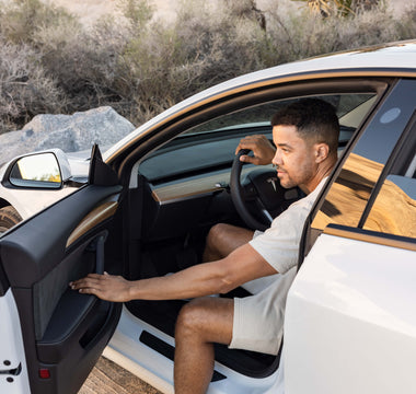 A man opening the door on the driver seat of a Tesla car